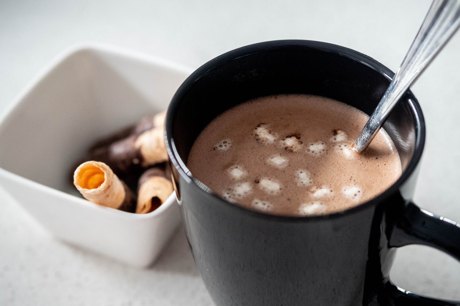 hot choco in black mug beside white bowl