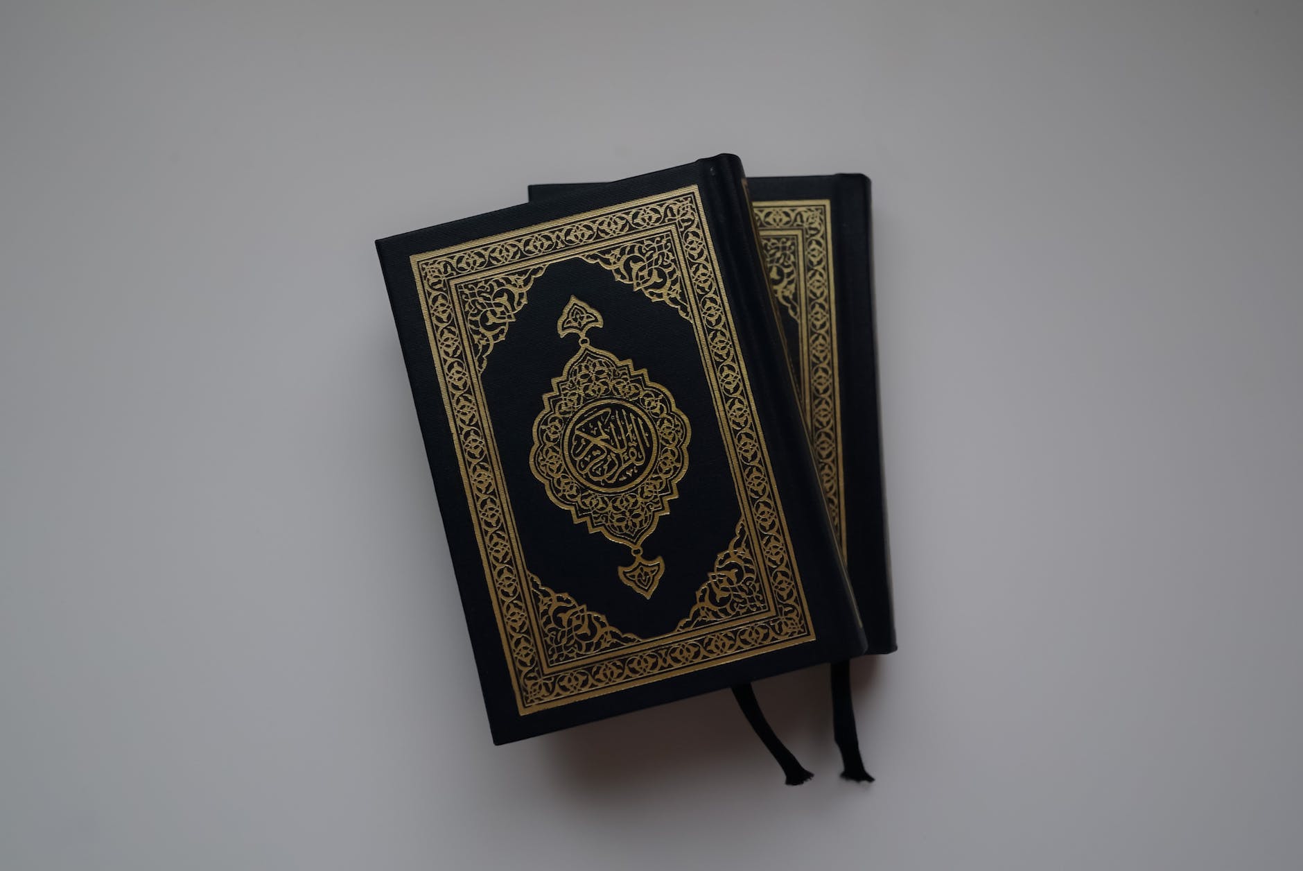 stacked quran on gray surface